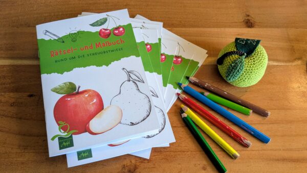 Stapel Malbücher mit bunten Stiften und gehäkeltem Apfel