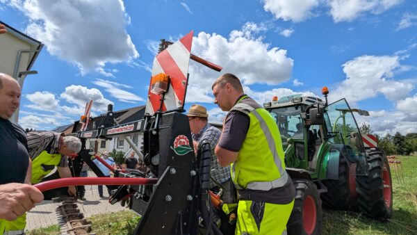 Männer stehen vor einem Traktor mit Doppelmessermähwerk
