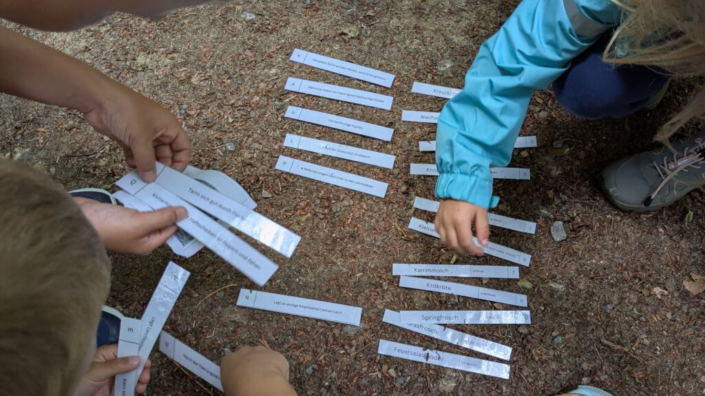 Kinder legen Streifen mit Text auf Boden
