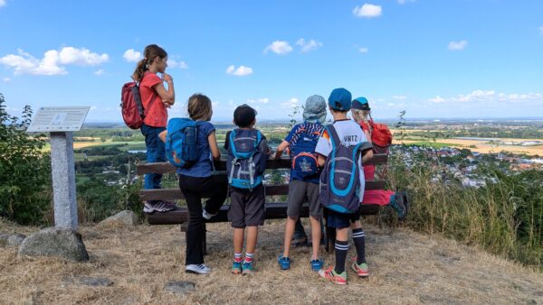 Kinder stehen an einer Bank und schauen in die Landschaft